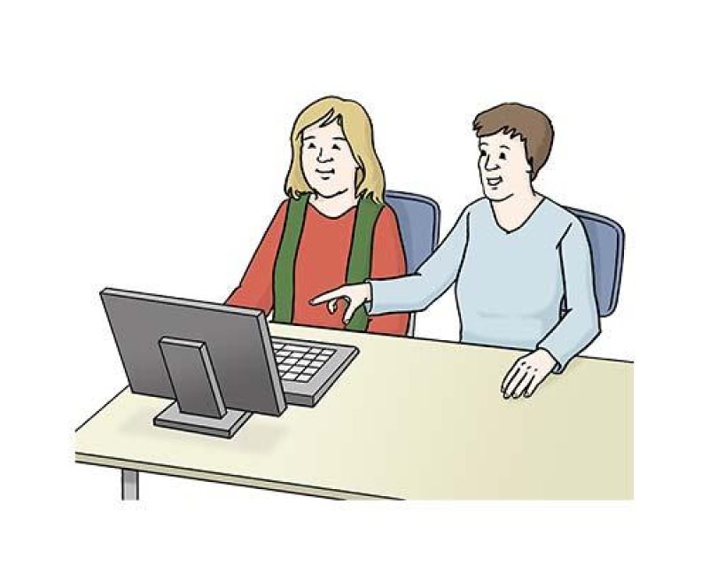 Zwei Personen sitzen an einem Computer, eine zeigt auf den Bildschirm.