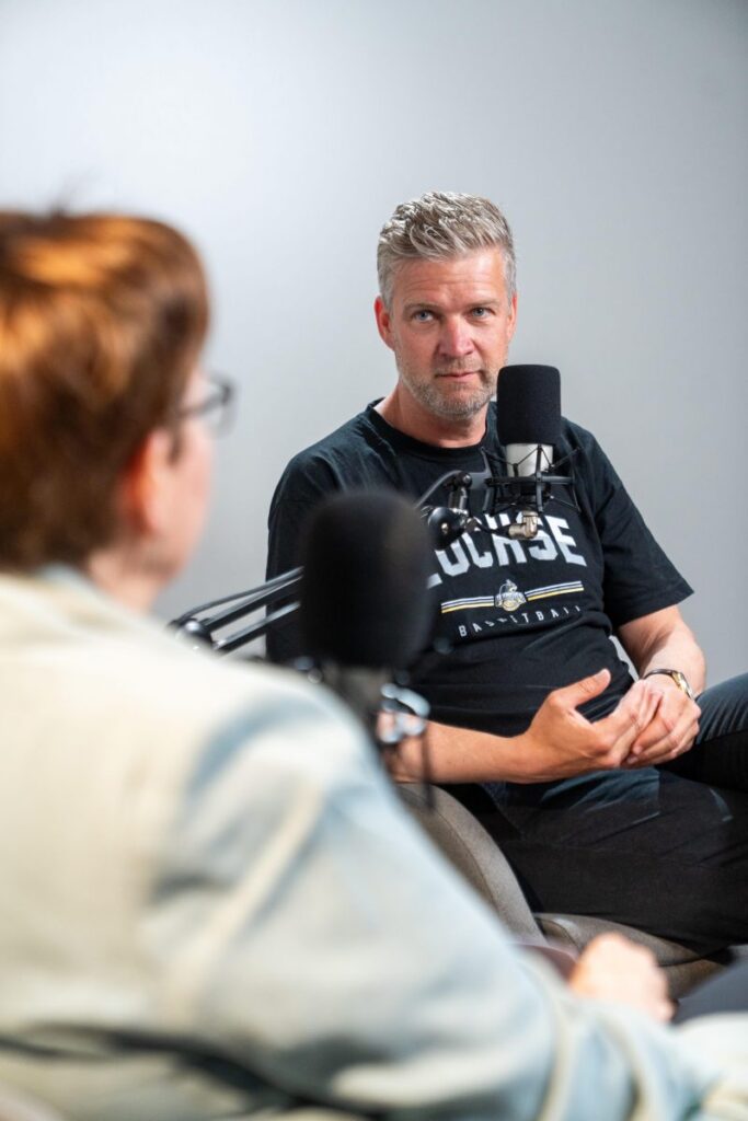 Hajo Rosenbrock sitzt im Podcast-Studio vor einem Mikrofon und spricht mit seinem Gegenüber.