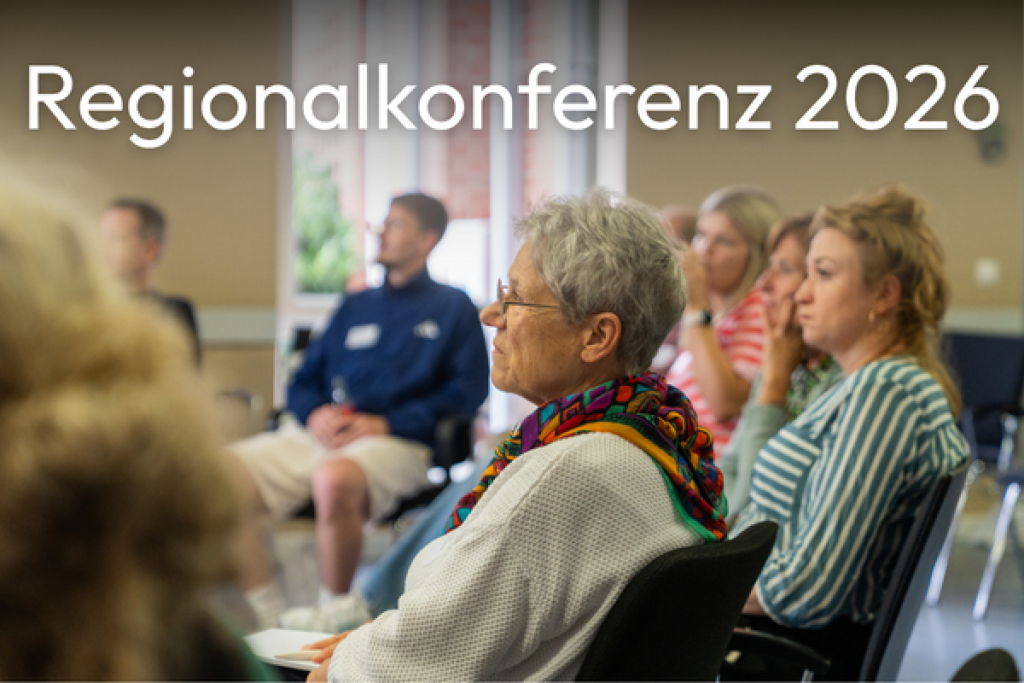 Teilnehmende sitzen auf Stühlen und hören aufmerksam zu. Darüber steht der Schriftzug „Regionalkonferenz 2026“